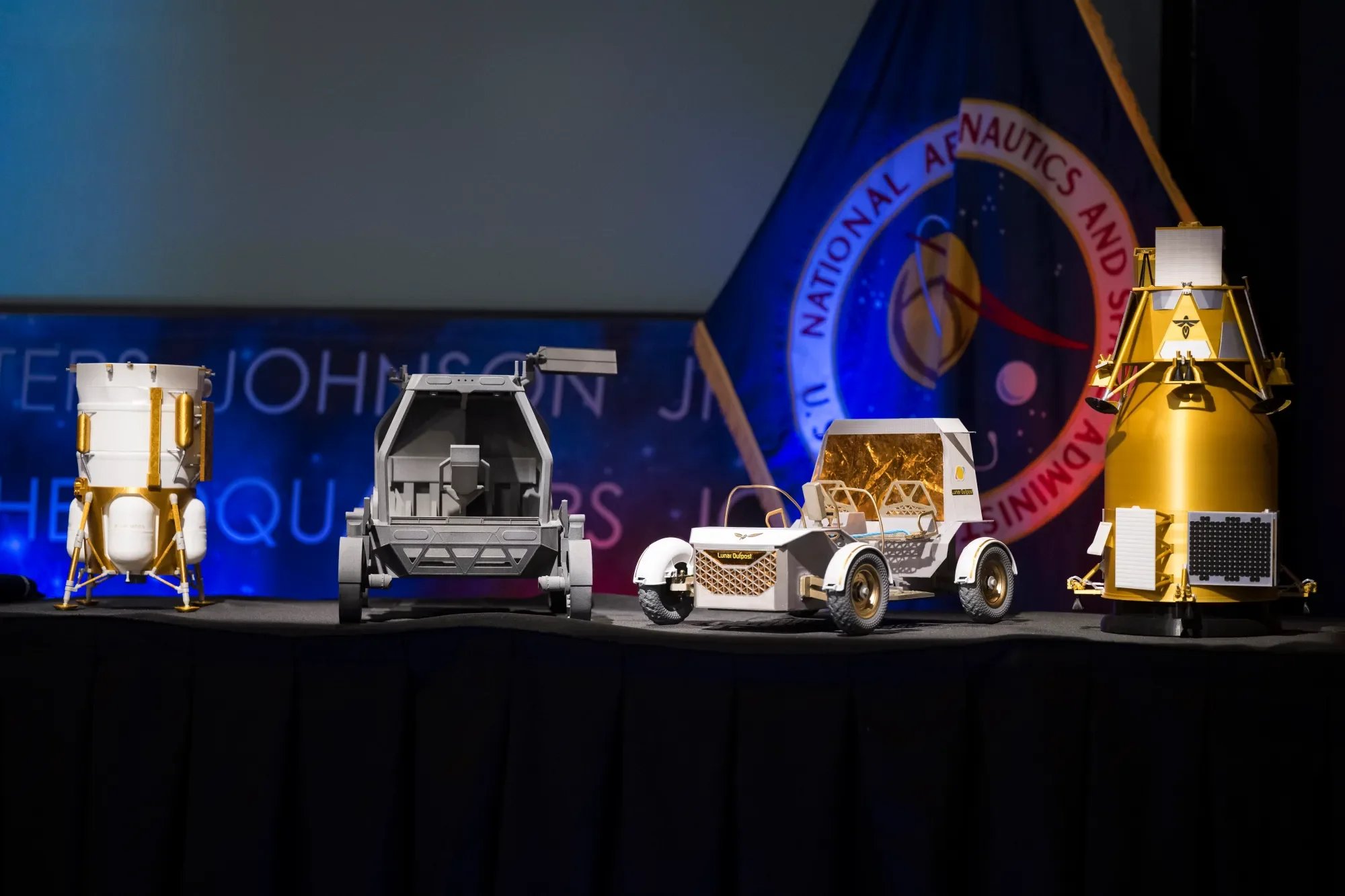 From left to right, models of the Blue Origin Mark 1 Lunar Lander, Astrolab Crewed Lunar Rover, Lunar Outpost Pegasus rover, and the Firely Elytra Dark orbiter are seen at the conclusion of a news conference to discuss Moon Base, a long-term lunar exploration and infrastructure initiative designed to enable sustained human presence and expanded scientific and commercial activity at the lunar South Pole, Tuesday, May 26, 2026, at the Mary W. Jackson NASA Headquarters building in Washington. Credit: NASA/Aubrey Gemignani
